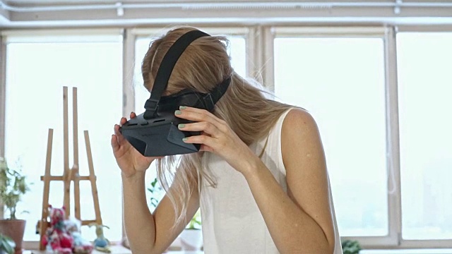 慢动作的金发女人在白色空间尝试虚拟现实眼镜。