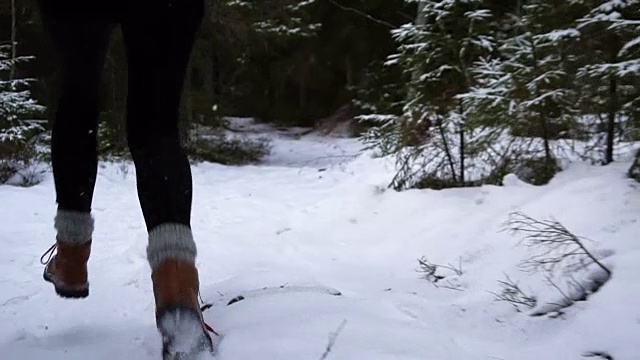 年轻女子在白雪覆盖的森林里奔跑