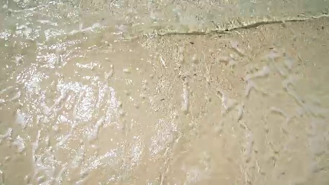 一个男人站在海滩上。白色的沙子和清澈的水。第一人称视角