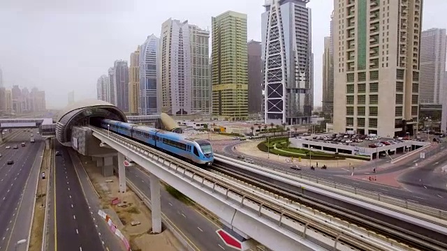 火车在阿联酋迪拜摩天大楼之间的高速公路上越过高架桥