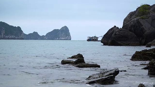 那艘钓鱼帆船航行在岩石之间的海上