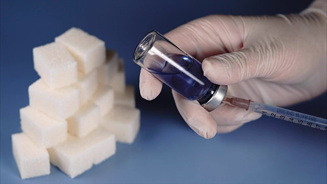 糖尿病的概念。方糖和胰岛素安瓿注射器。