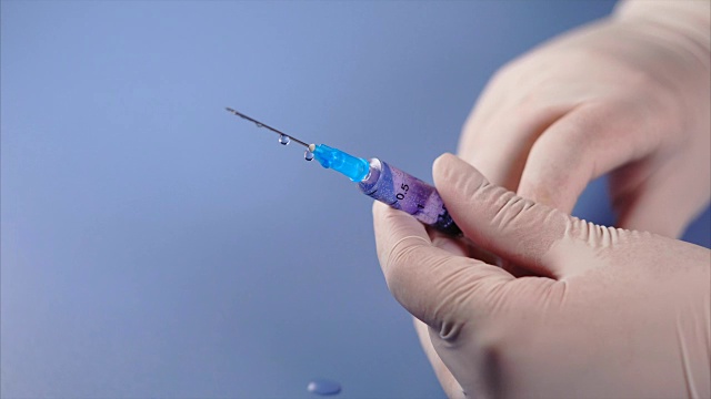 医生手里拿着注射器。药物从注射器中漏出。