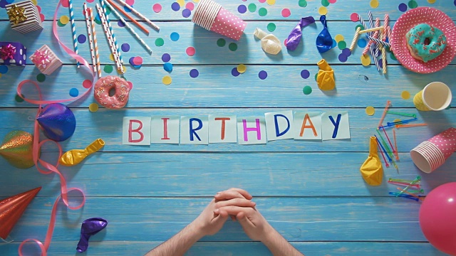 頂視圖的人把“生日”字放在桌子上，上面裝飾著生日