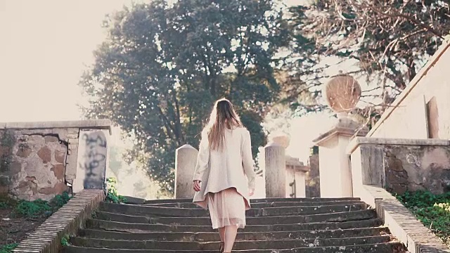年轻时尚的女子走在城市老街上，爬着楼梯。在欧洲度假的女孩