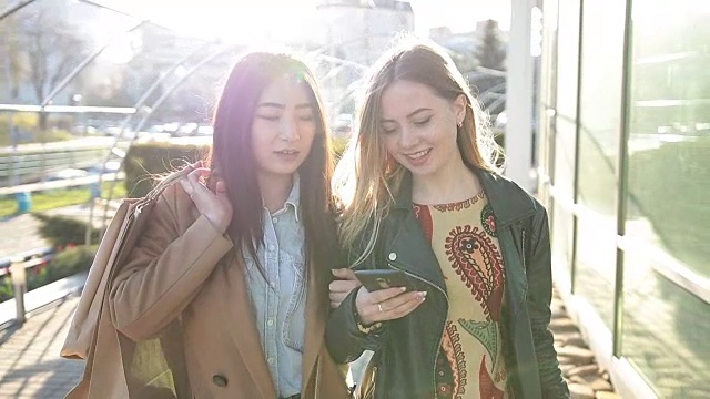 两个年轻女人在街上看智能手机