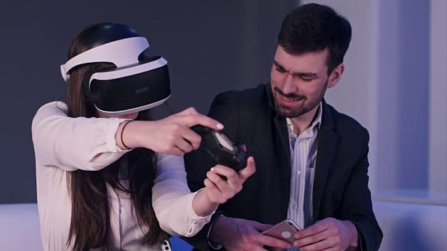 詳情圖-帶著手機微笑的年輕男子試圖阻止戴著VR頭盔的女孩玩得太多