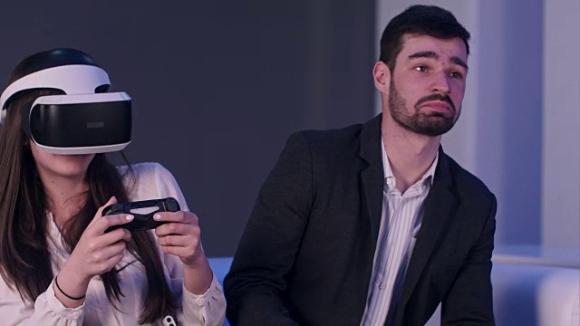 詳情圖-帶著手機微笑的年輕男子試圖阻止戴著VR頭盔的女孩玩得太多