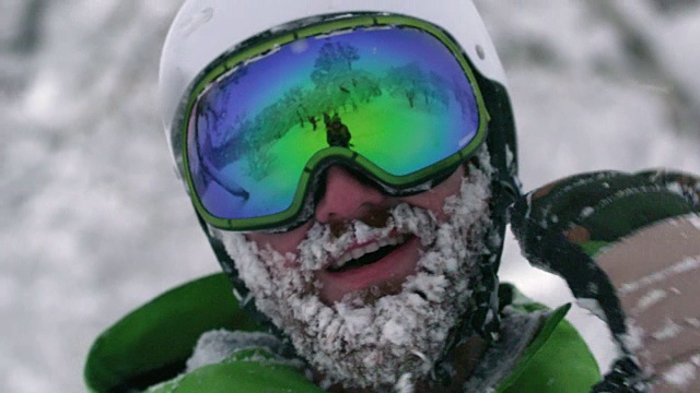 戴着头盔的滑雪者滑雪者登山运动员大胡子满是雪花从冰冻的脸上摇下来