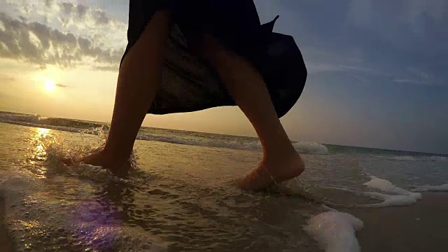 一名女子在日落时分沿着海滩行走的4K实时视频