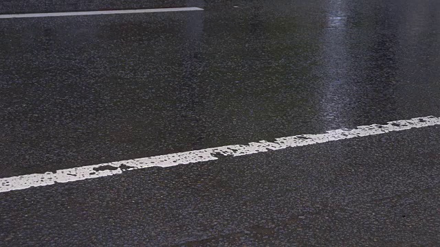 沥青路上下着大雨，车辆往来。