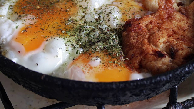 在平底锅里煎鸡蛋和香料炸鸡块