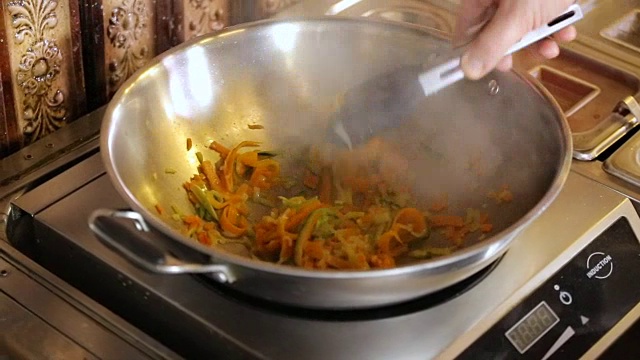 厨师在平底锅中混合蔬菜意面
