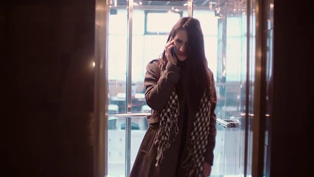 电梯门开着。一个女人站在电梯里一边打电话一边走了