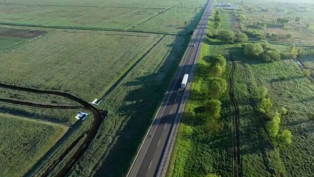 詳情圖-一輛卡車在太陽升起的綠色田野之間的道路上行駛的全高清航拍鏡頭