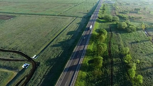詳情圖-一輛卡車在太陽升起的綠色田野之間的道路上行駛的全高清航拍鏡頭