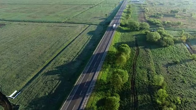 詳情圖-一輛卡車在太陽升起的綠色田野之間的道路上行駛的全高清航拍鏡頭
