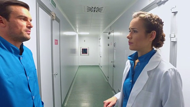 两位科学家在实验室走廊里交谈。科学男人和女人聊天