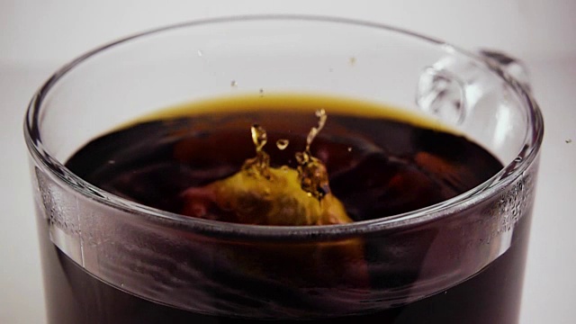 柠檬滴进一杯茶里。慢动作