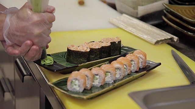 厨师在餐厅厨房里用芥末装饰现成的寿司卷