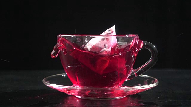 在透明的茶杯里洒茶袋，慢动作