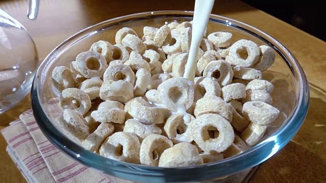 脆燕麦片在碗里，早餐美味的牛奶。慢动作旋转跟踪镜头。