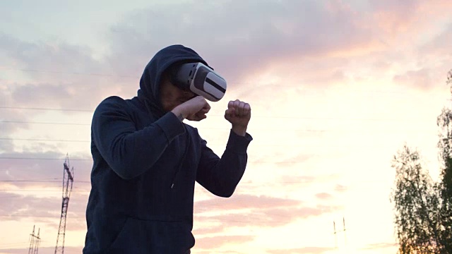 詳情圖-剪影的年輕男子拳擊手在VR,360耳機(jī)訓(xùn)練踢在城市公園日落在虛擬現(xiàn)實(shí)戰(zhàn)斗