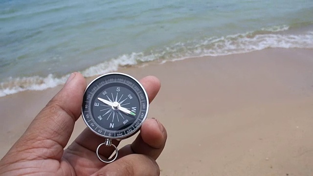 近景拍摄手握指南针在沙滩上与自然，大海和风的环境声音