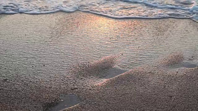 沙滩上的海浪在夕阳下的海洋海洋夏天的足迹