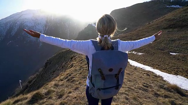 女性徒步旅行者在山顶张开双臂