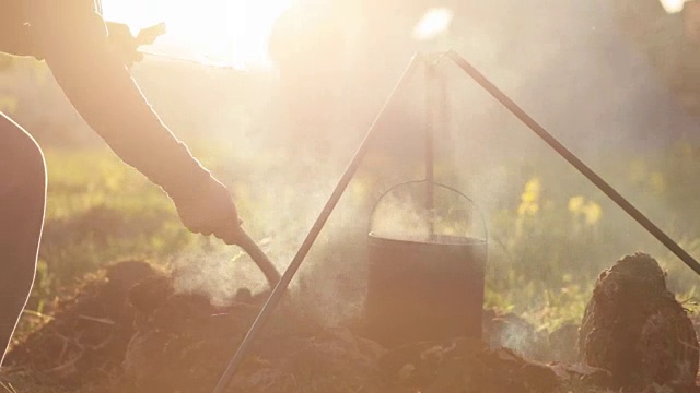 白人男子烹饪食物在booler在篝火露营。