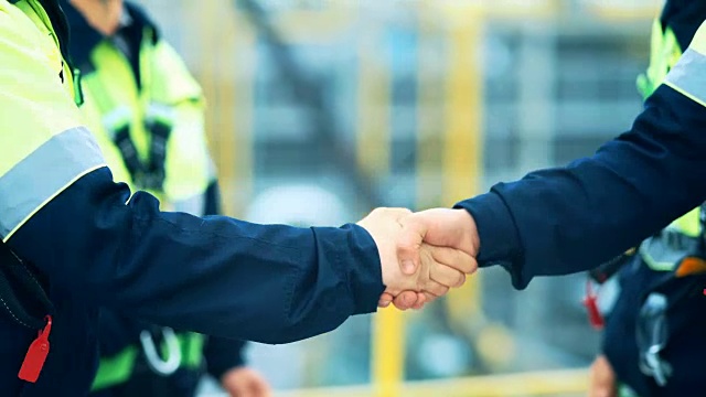 承包商在一家工厂前握手结束一项交易