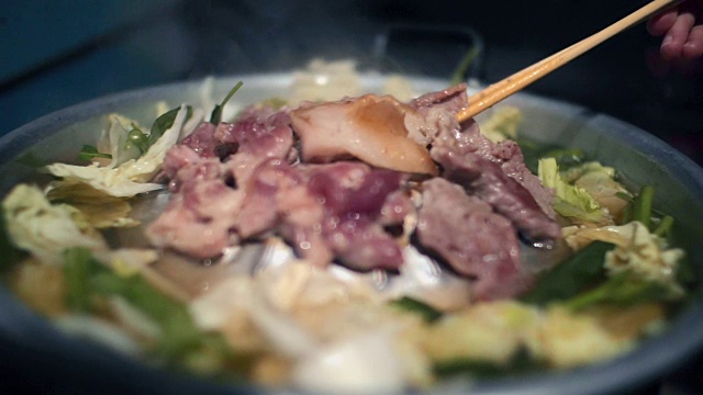 韩式烧烤:女人用手在热气腾腾的平底锅上翻肉