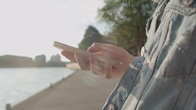 近距离的年轻女性的手使用电话，户外。