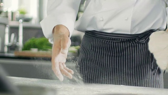 著名餐厅的面包师在现代化的厨房里揉面。