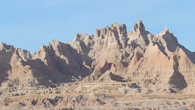 近距离观察:在Badlands NP，陡峭的尖砂岩山脉映衬着清澈的蓝天