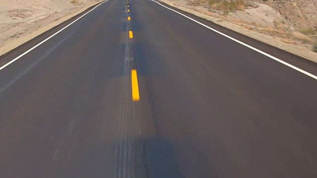 空中飞行在空旷的公路上穿过广阔的沙漠，秋天的犹他州，美国