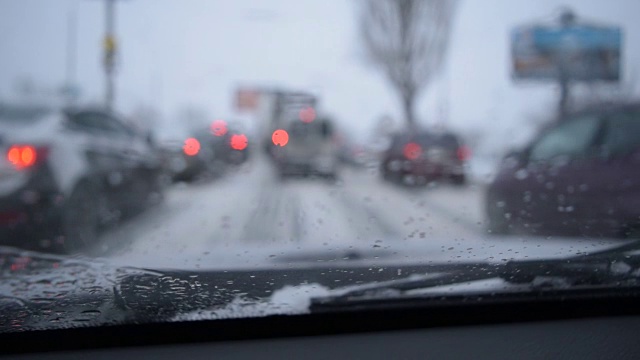 透过挡风玻璃看散焦的场景在下雪的城市道路