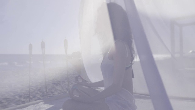 在海滩上沉思的女人，在度假胜地的暑假，女孩在海滩上做瑜伽，在海岸上沉思