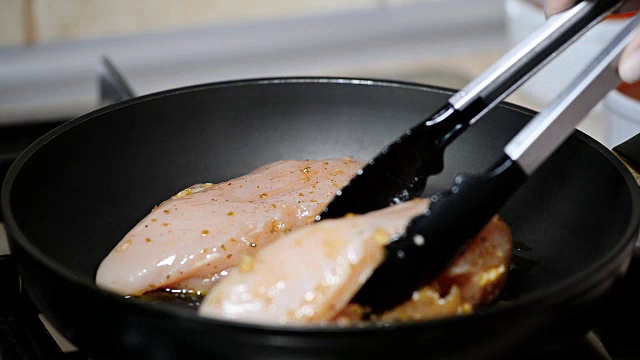 在煎锅里炸鸡肉。把肉放到锅里