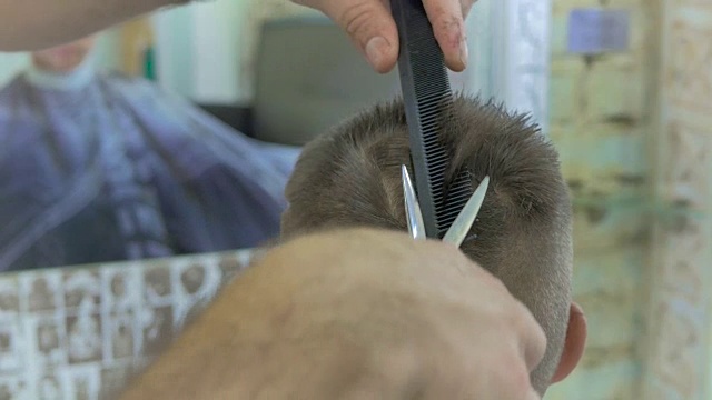 专业发型师在理发店用剪刀为小男孩剪头发