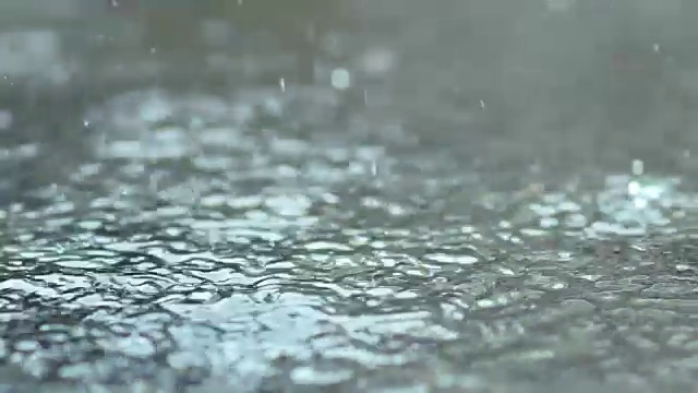 水飞溅。雨水缓慢地落在水坑上