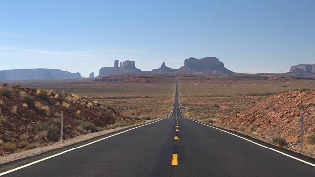 低角度视角:笔直的空道路，通往美国犹他州的标志性纪念碑谷