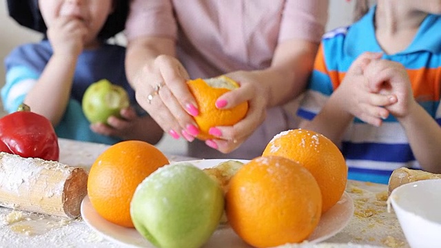 孩子们和他们的妈妈在厨房刷水果。儿童处理特写