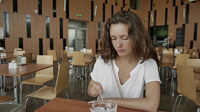 那个女孩正在吃早饭。小女孩在咖啡馆里