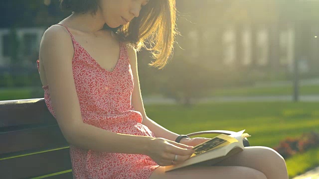 女孩在公园里看书，在夏天的夕阳下