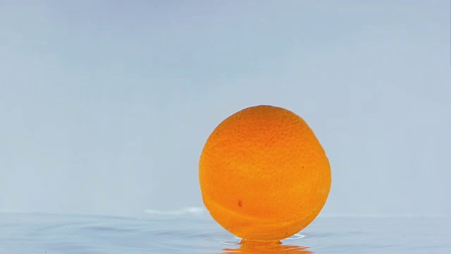 一个橙子在水面上碰撞的慢镜头。