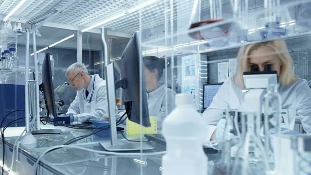 在一个新的高科技实验室使用显微镜和医学数据的研究科学家团队。