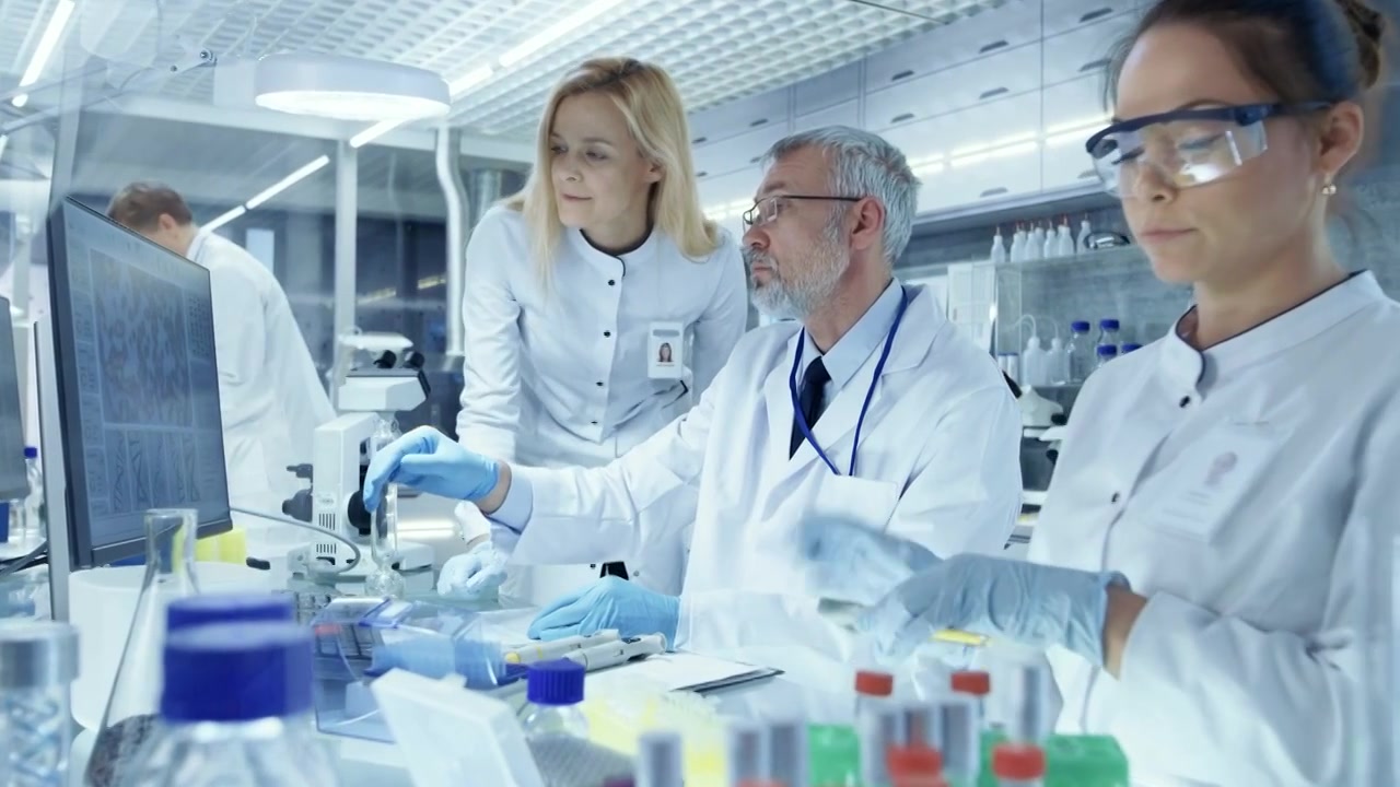 详情图-研究科学家团队使用个人计算机，分析试验试验新一代药物数据。他们在一个现代化的实验室/医疗中心工作。