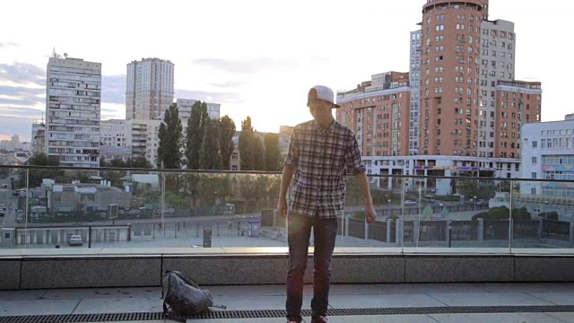 时髦快乐的亚洲学生舞者男子街头舞自由式在城市在日落